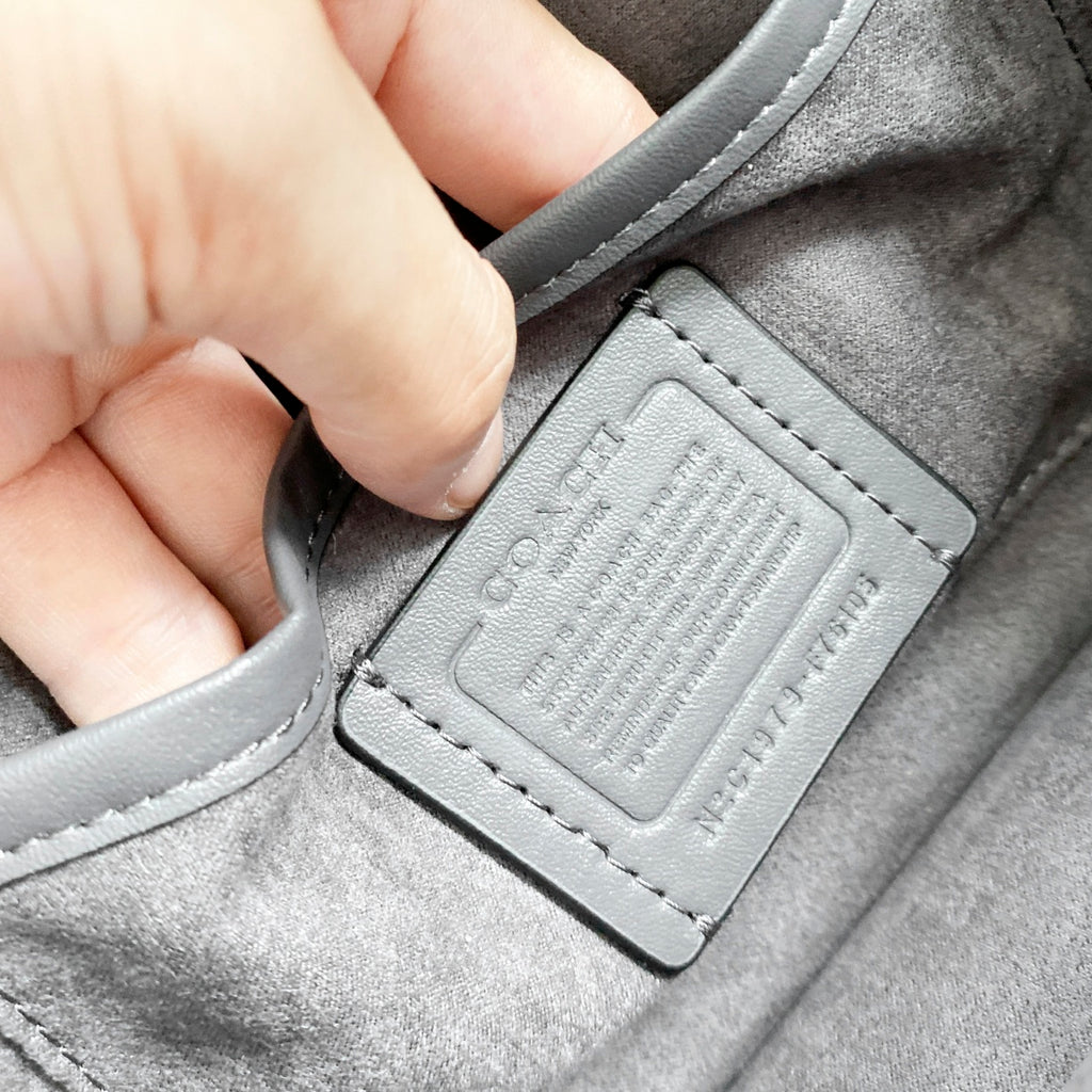 Coah bag close-up of gray logo label patch with stitching on inner pocket