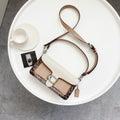Coah bag with top handle, white flap, and brown patterned side panels with metal clasp.