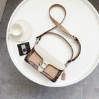 Coah bag with top handle, white flap, and brown patterned side panels with metal clasp.