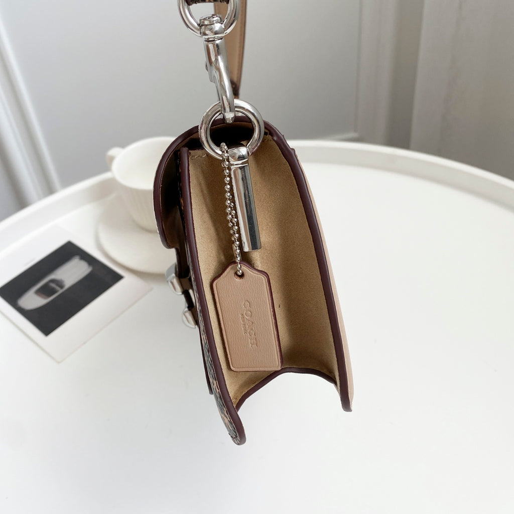 Coah bag open view showing interior pocket, metal zipper pull, and hanging brand tag.