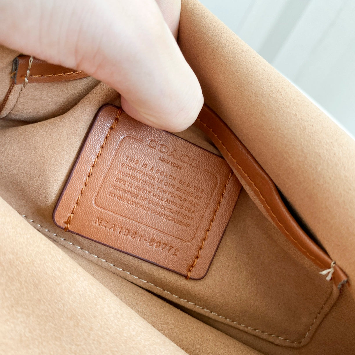 Coah bag close-up of leather tag and stitched edge on the interior flap area.