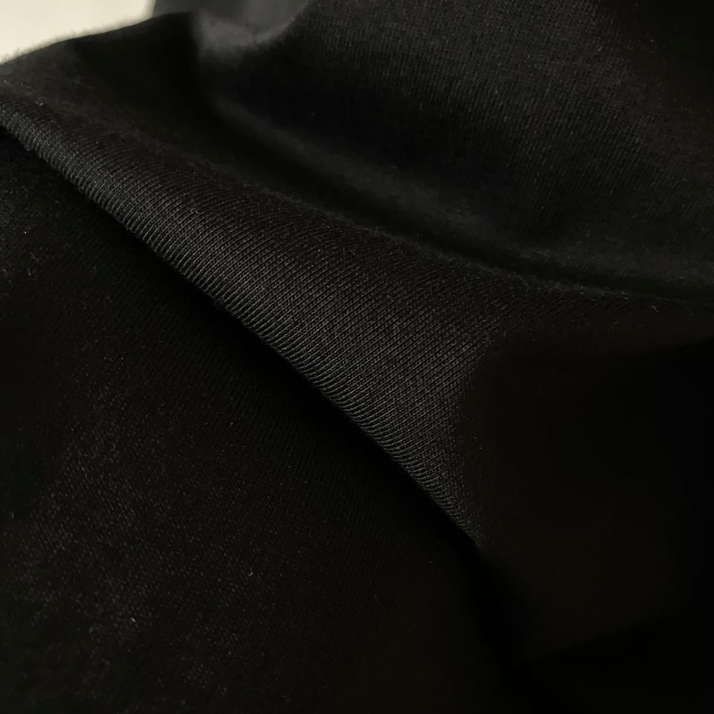 Black T-shirt fabric close-up, smooth knit with subtle texture
