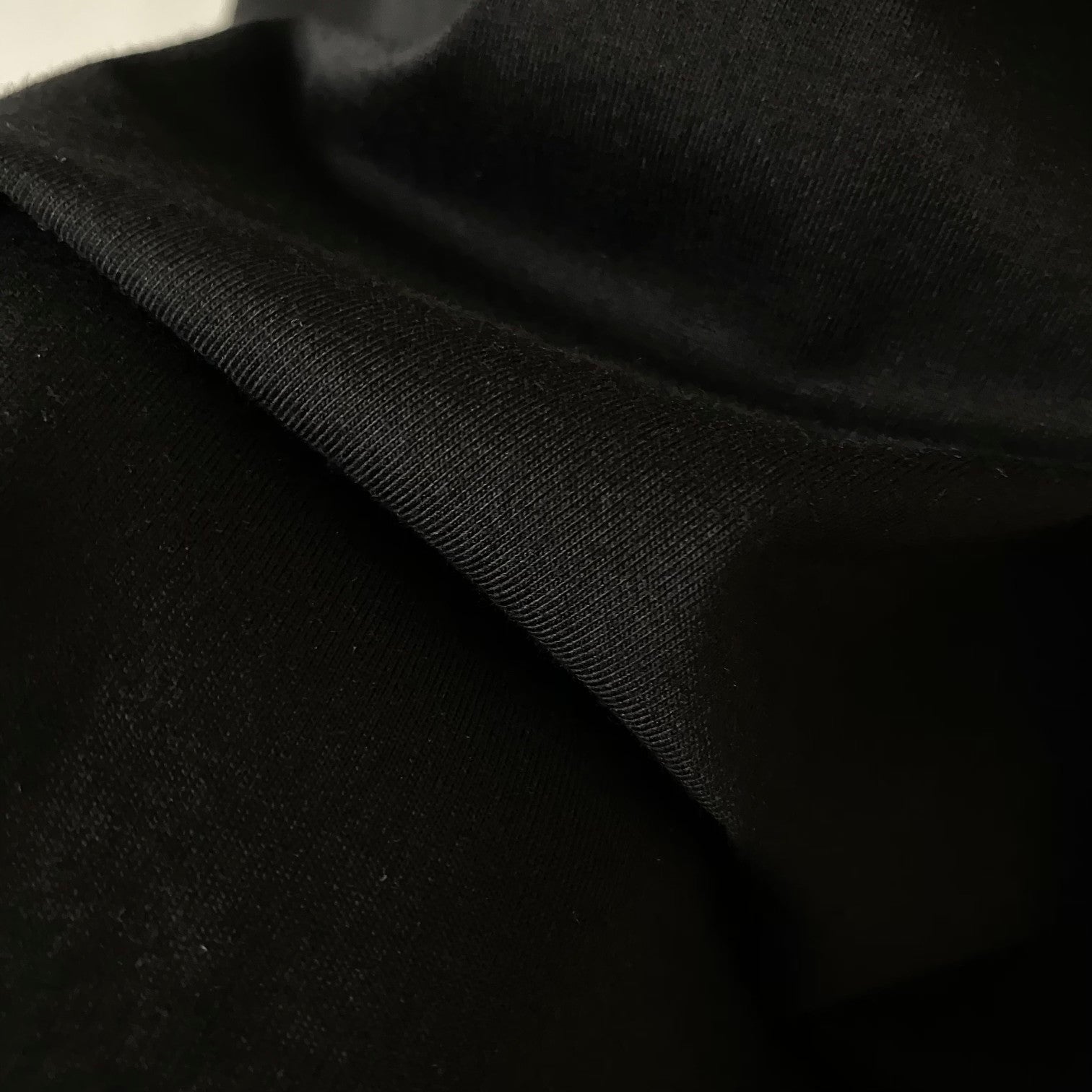 Black T-shirt fabric close-up, smooth knit with subtle texture