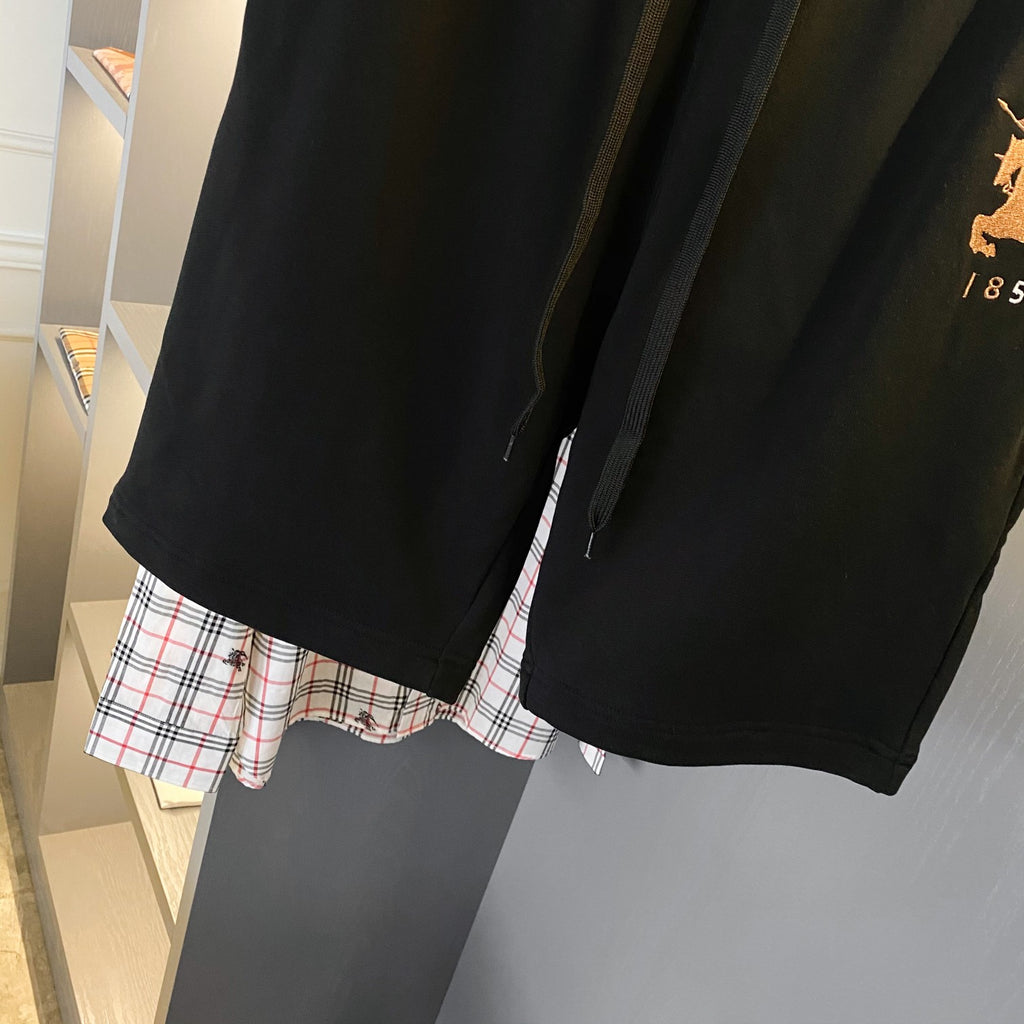 Black Burberry drawstring shorts with plaid lining peeking at the hem