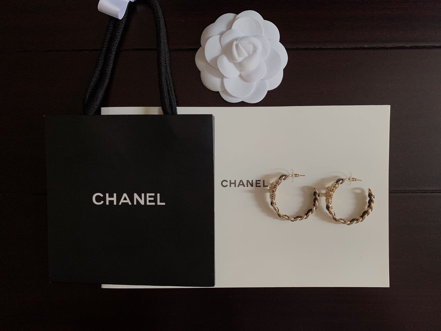 Gold-tone chain hoop earrings with black enamel accents on display card