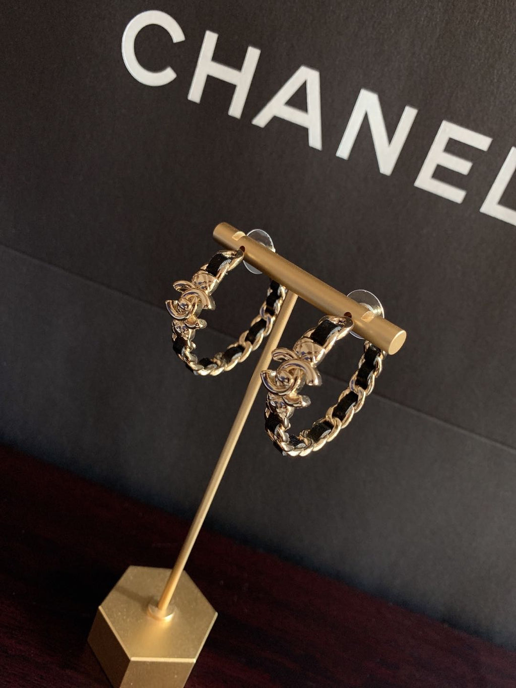 Gold-tone chain hoop earrings on stand with black enamel links
