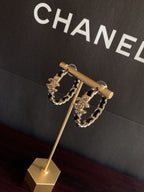 Gold-tone chain hoop earrings on stand with black enamel links