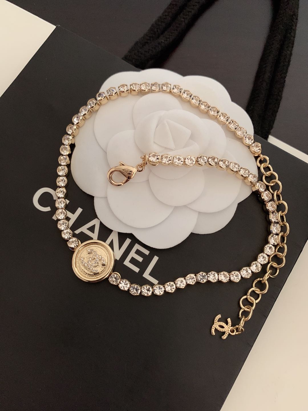 Gold-tone rhinestone chain bracelet with round logo coin medallion and linked charm drop