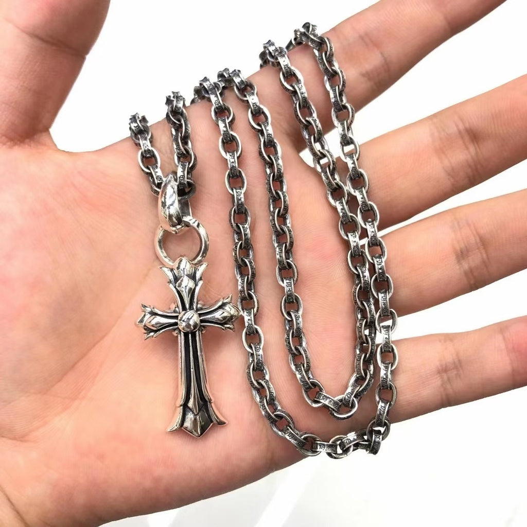Cross pendant necklace held in hand with silver-tone chain