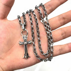 Cross pendant necklace held in hand with silver-tone chain