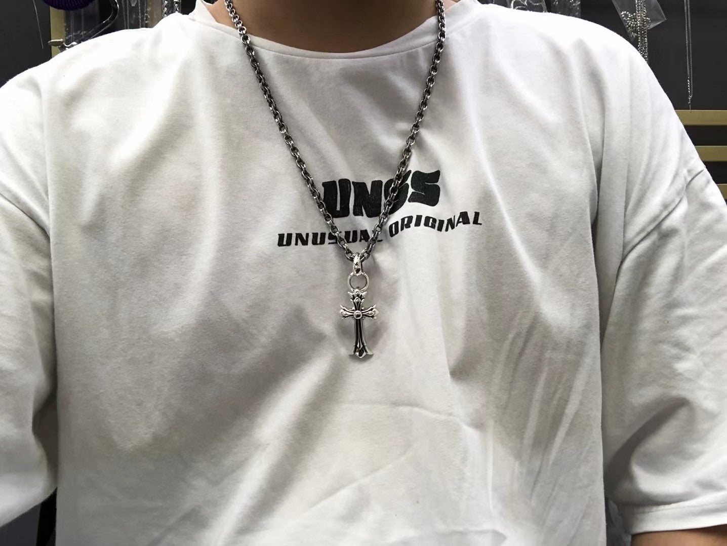 Cross pendant necklace worn over a white crewneck shirt