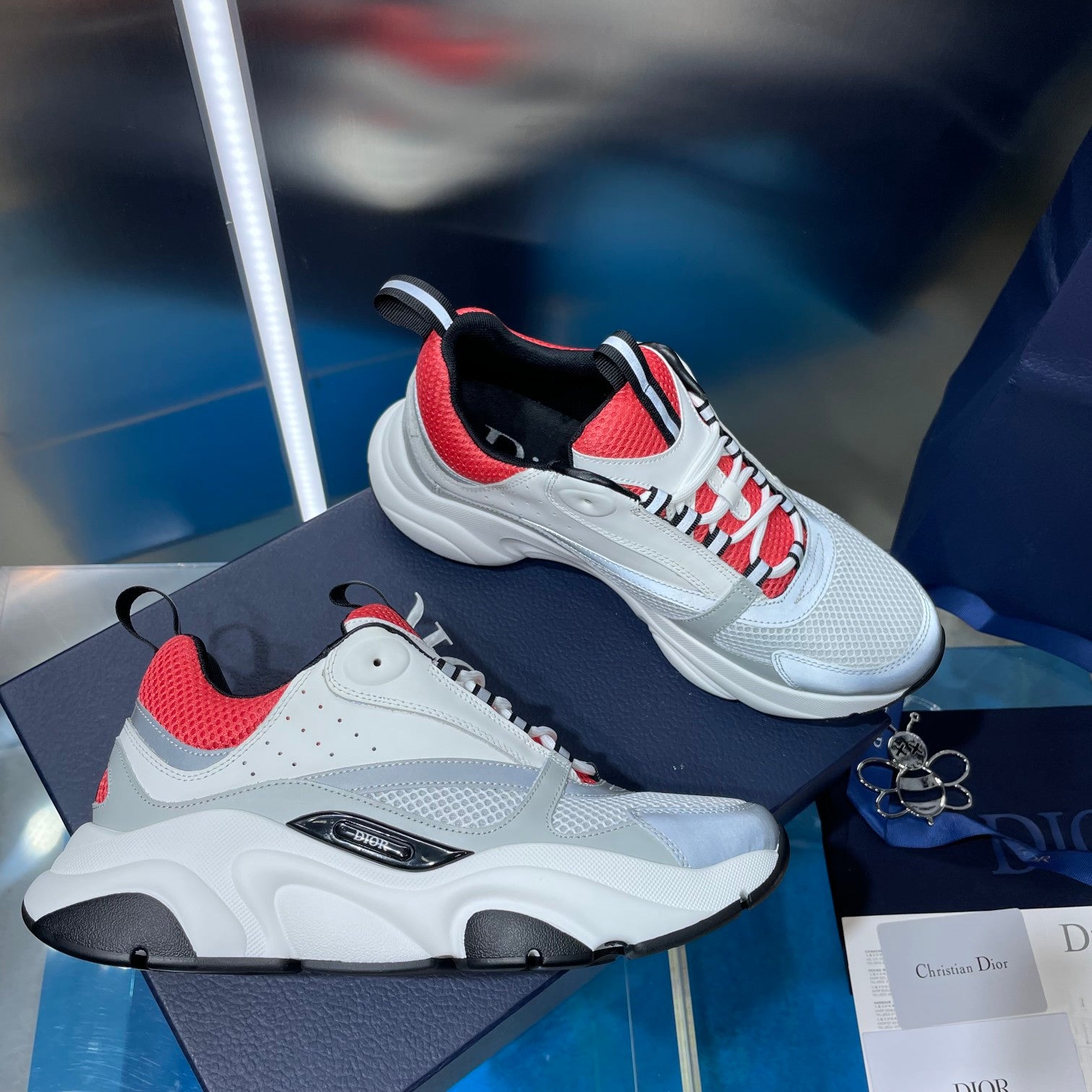 White lace-up sneakers with red mesh panels, black accents, and chunky sole.