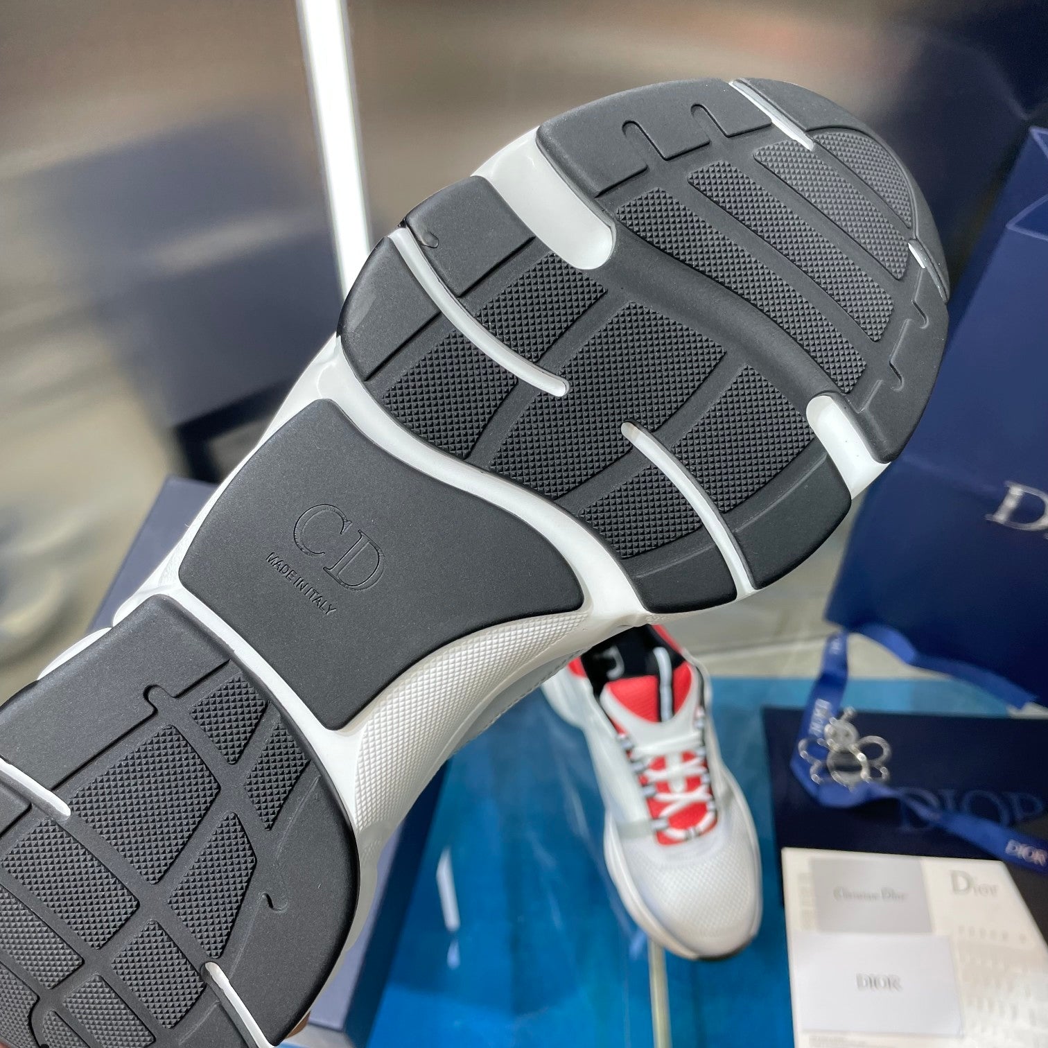 Outsole view of white sneakers with dark tread and molded tread pattern.