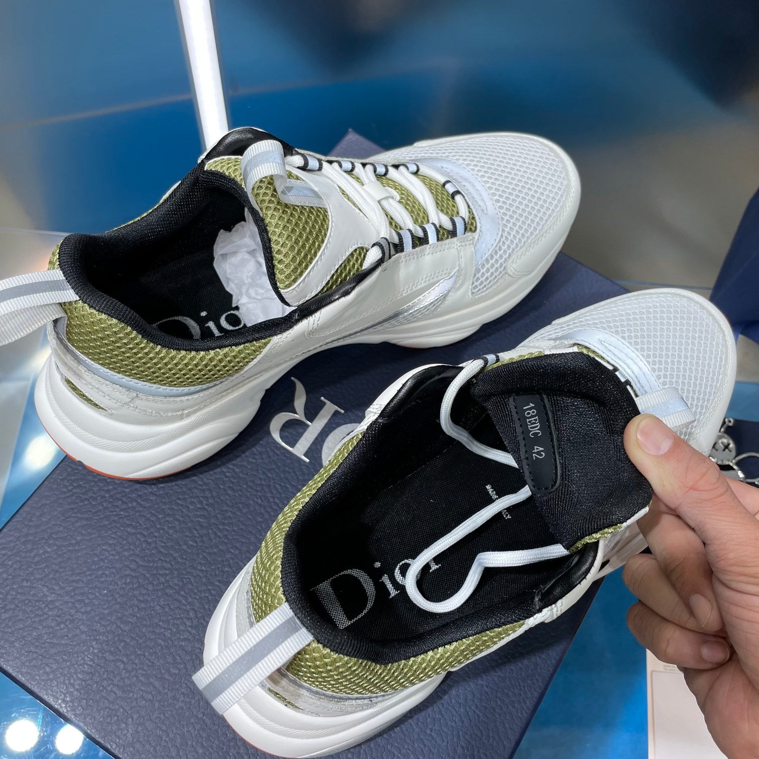 White sneakers with black interior and neon green trim, held by hand