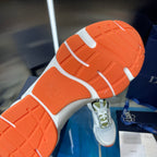 Orange and white outsole view of sneakers with textured tread