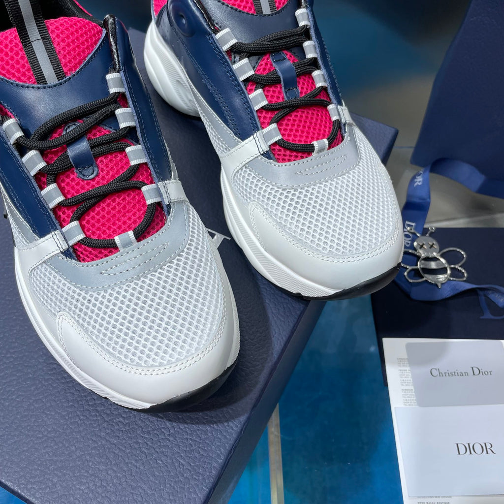 Close-up of white and navy sneakers with bright pink trim and plaid laces