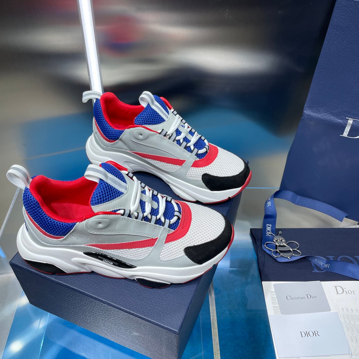 Dior unisex sneakers pair, white with blue and red trims, visible laces and toe
