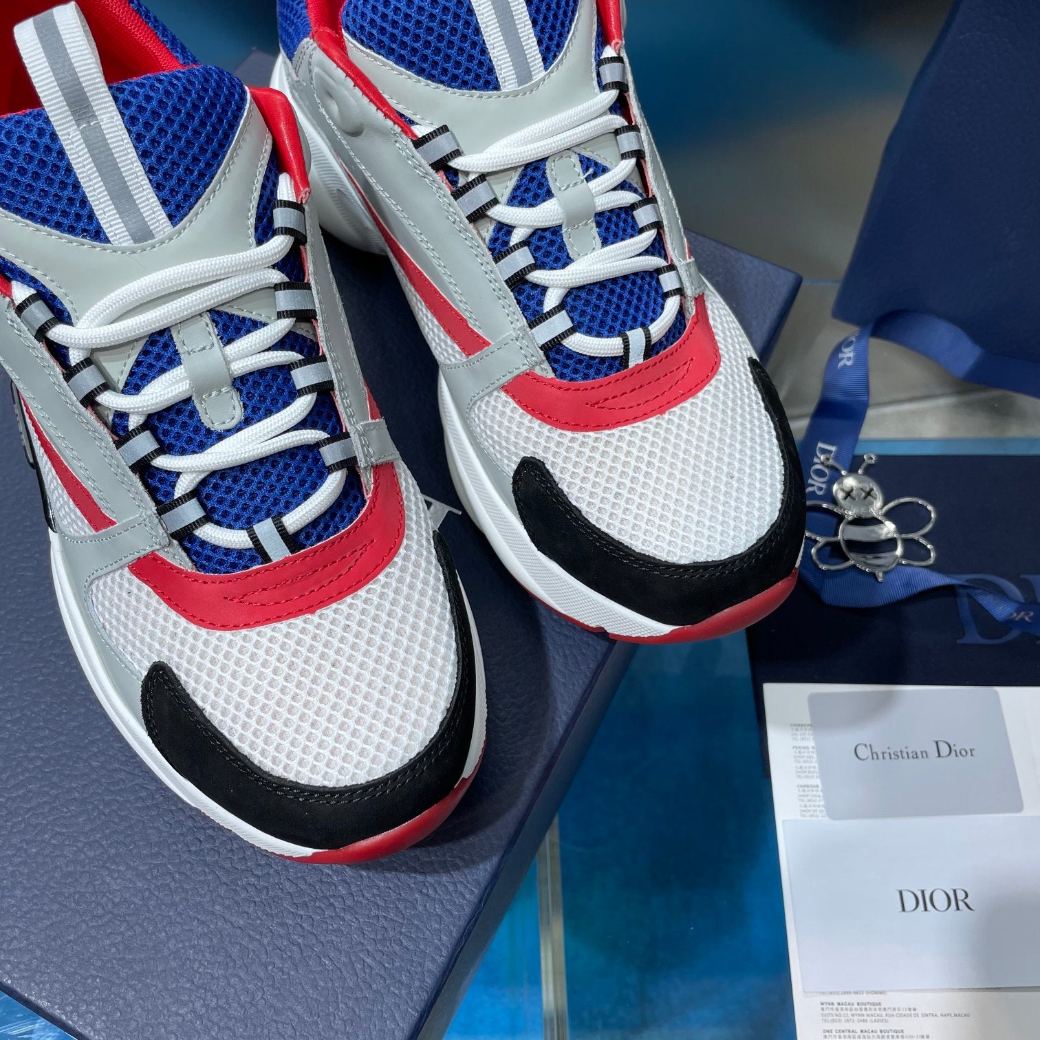 Dior unisex sneakers close-up, white and blue mesh with red stripe and laces