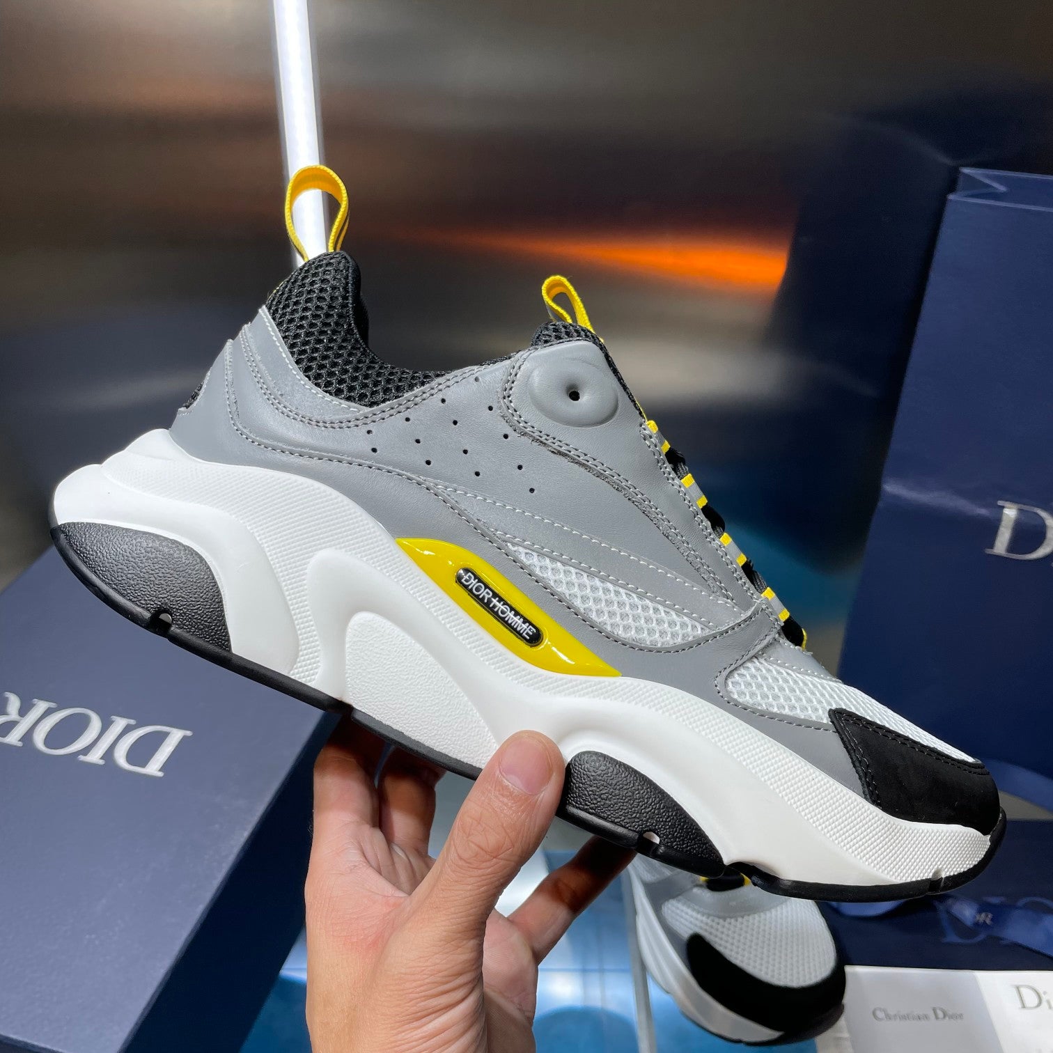 Single unisex sneaker, light gray leather with black sole and yellow side stripe