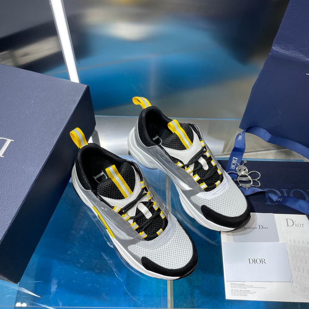 Pair of unisex sneakers, gray and black uppers with yellow lace accents, side view