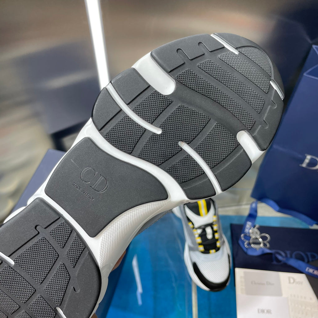 Unisex sneaker outsole view, dark tread with light gray bumper and logo patch