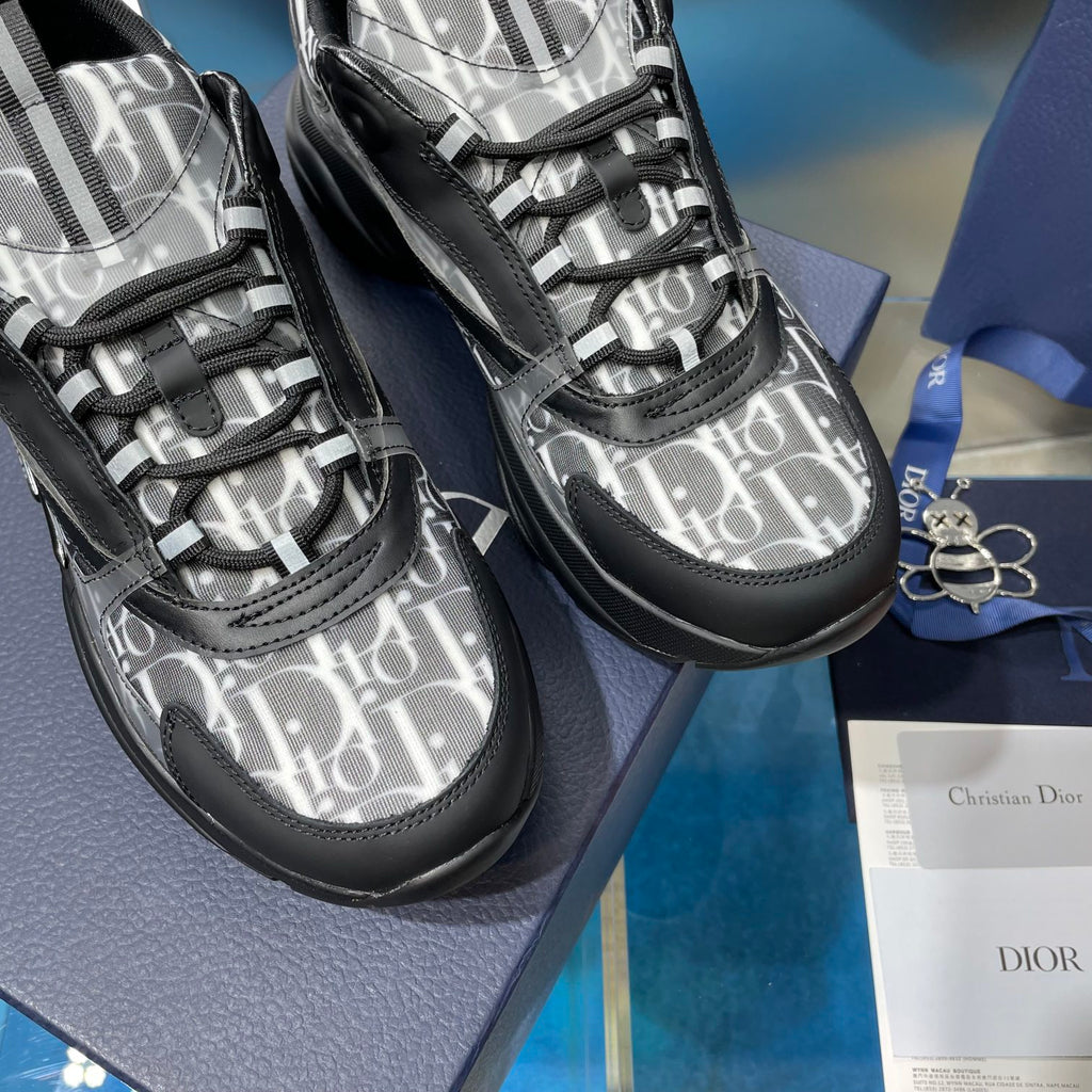 Close-up of lace-up sneakers with silver logo-print canvas and black textured trim
