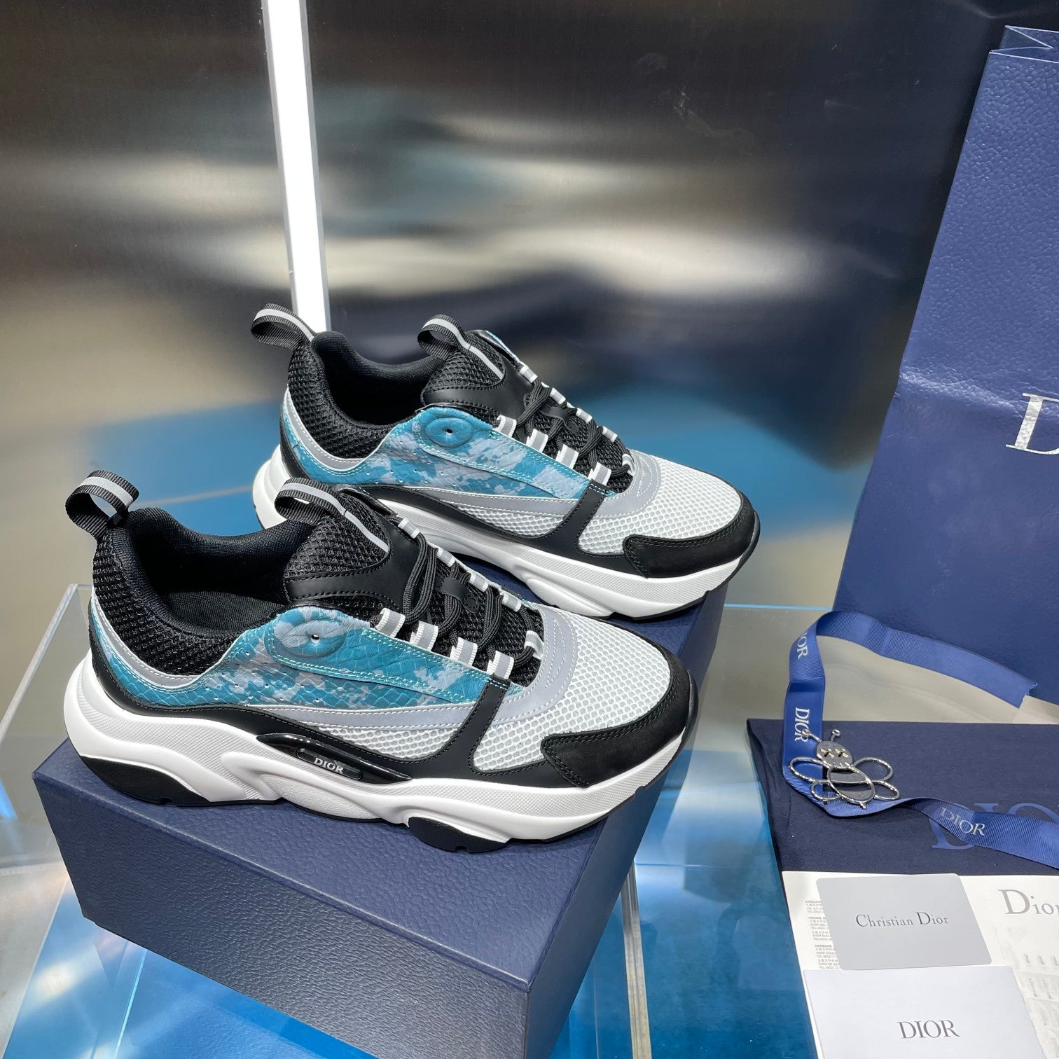 Pair of Dior unisex sneakers with black uppers, white panels, and light blue details