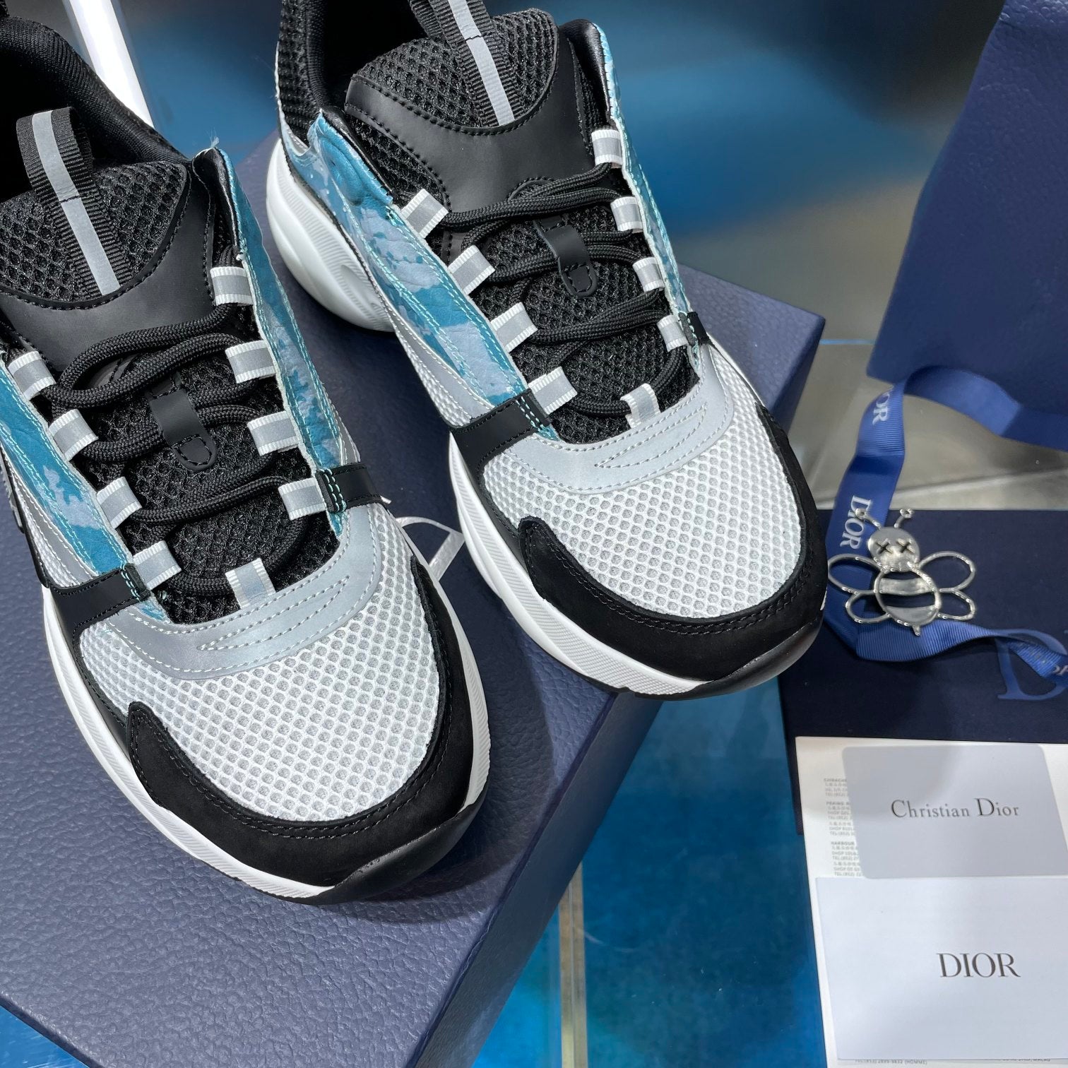 Dior unisex sneakers close-up showing textured white panels, black mesh, and light blue