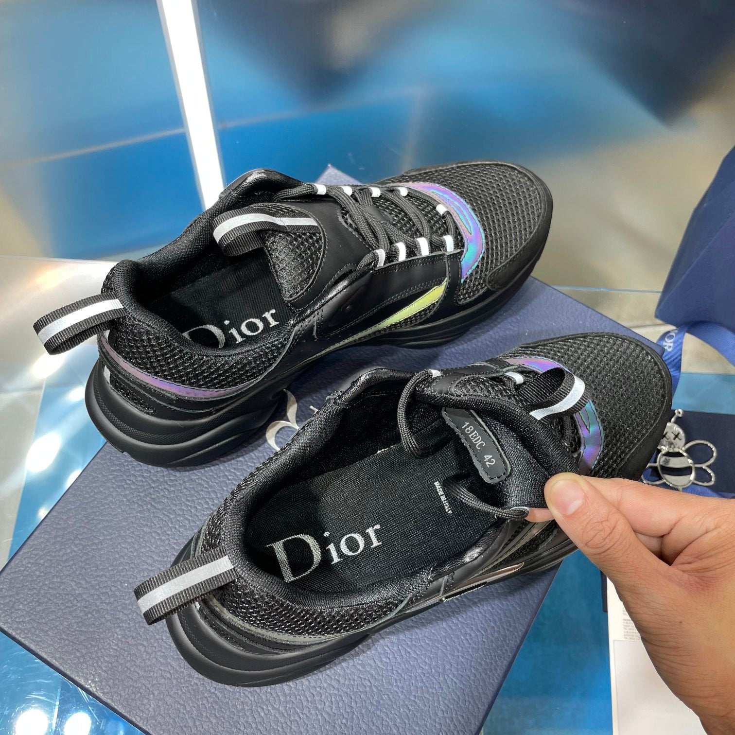 Black lace-up sneakers with visible Dior text on tongue and teal side trim