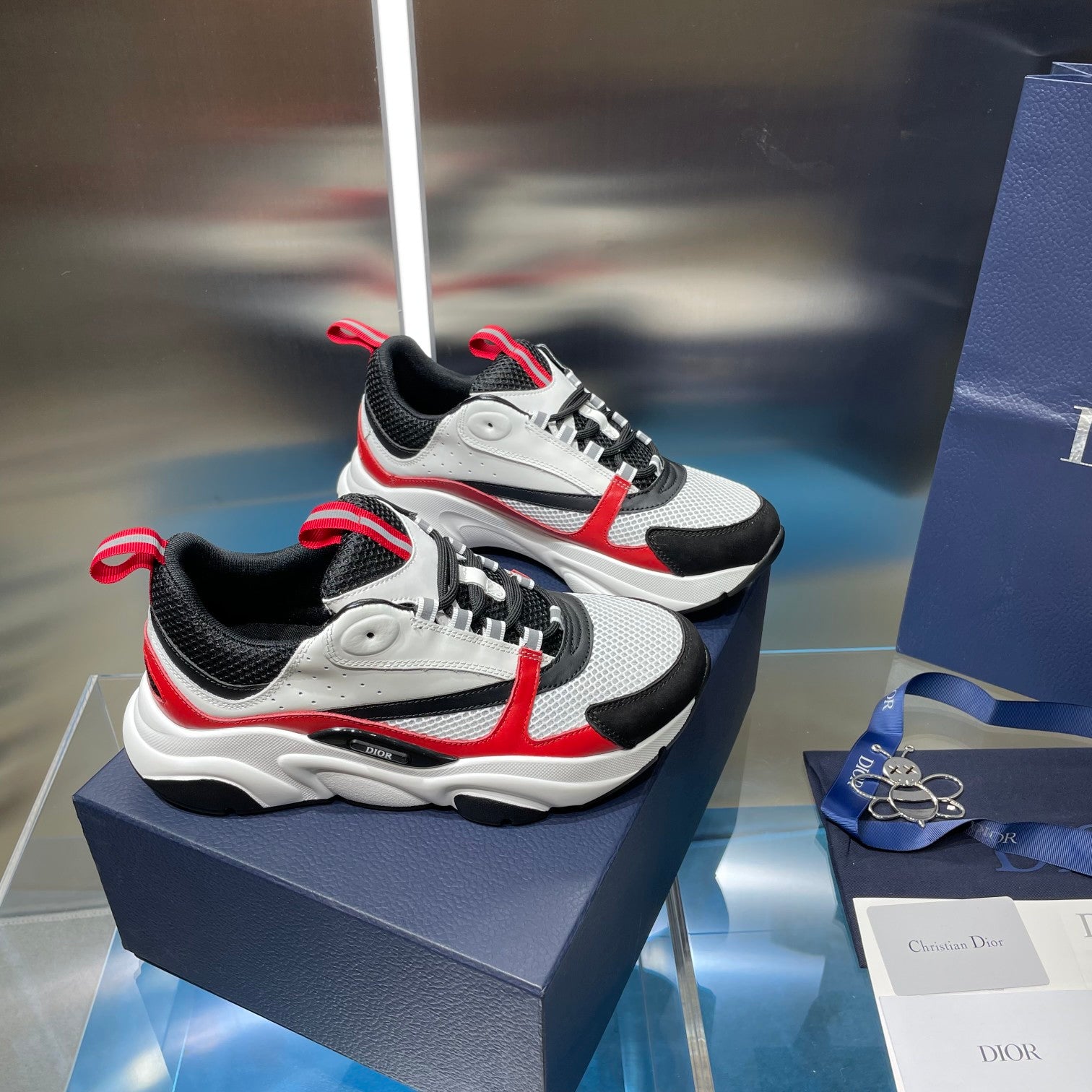 Pair of white, black and red lace-up sneakers with striped ankle detail and thick sole.