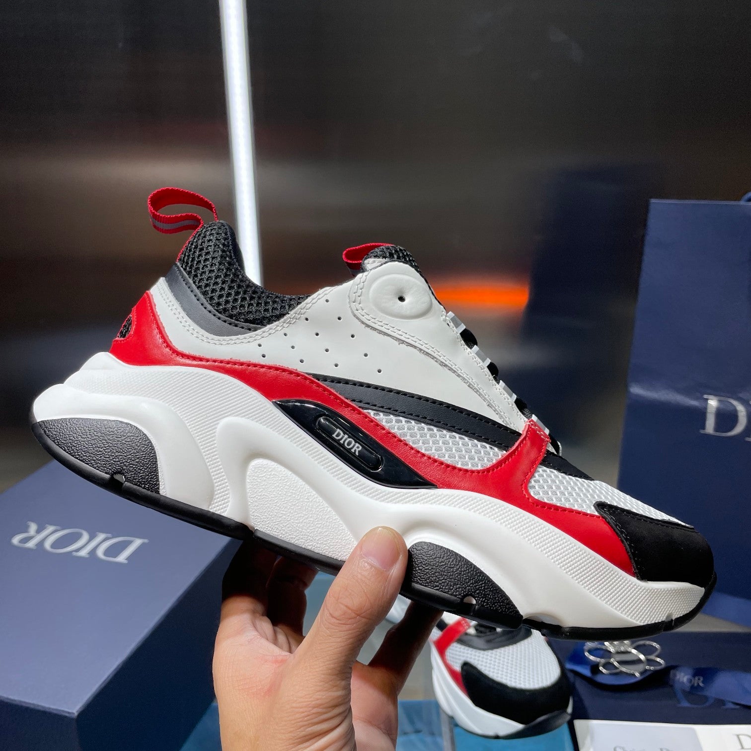 White and black sneakers with red side panel and chunky treaded outsole, side view.
