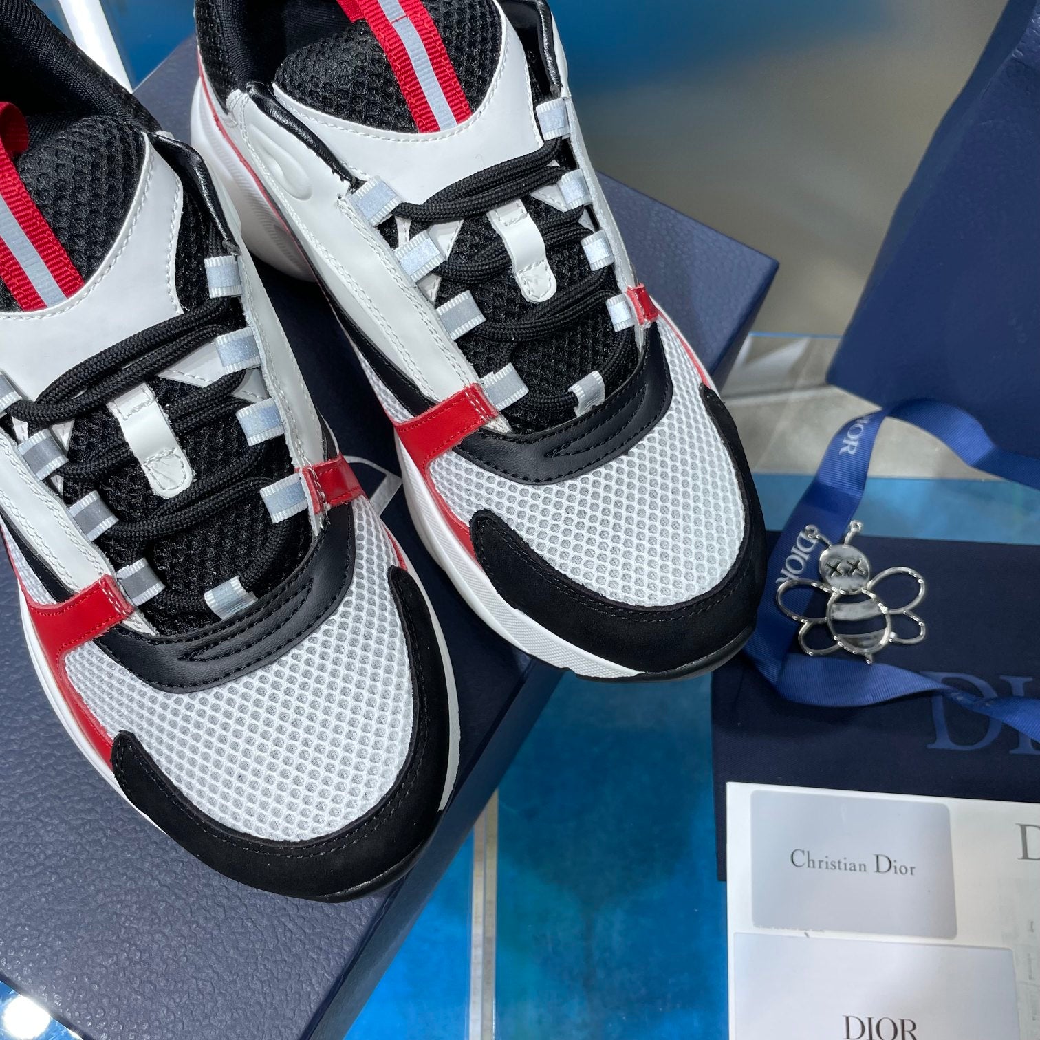 Close-up of white, black and red sneakers with mesh panels and lace-up front.