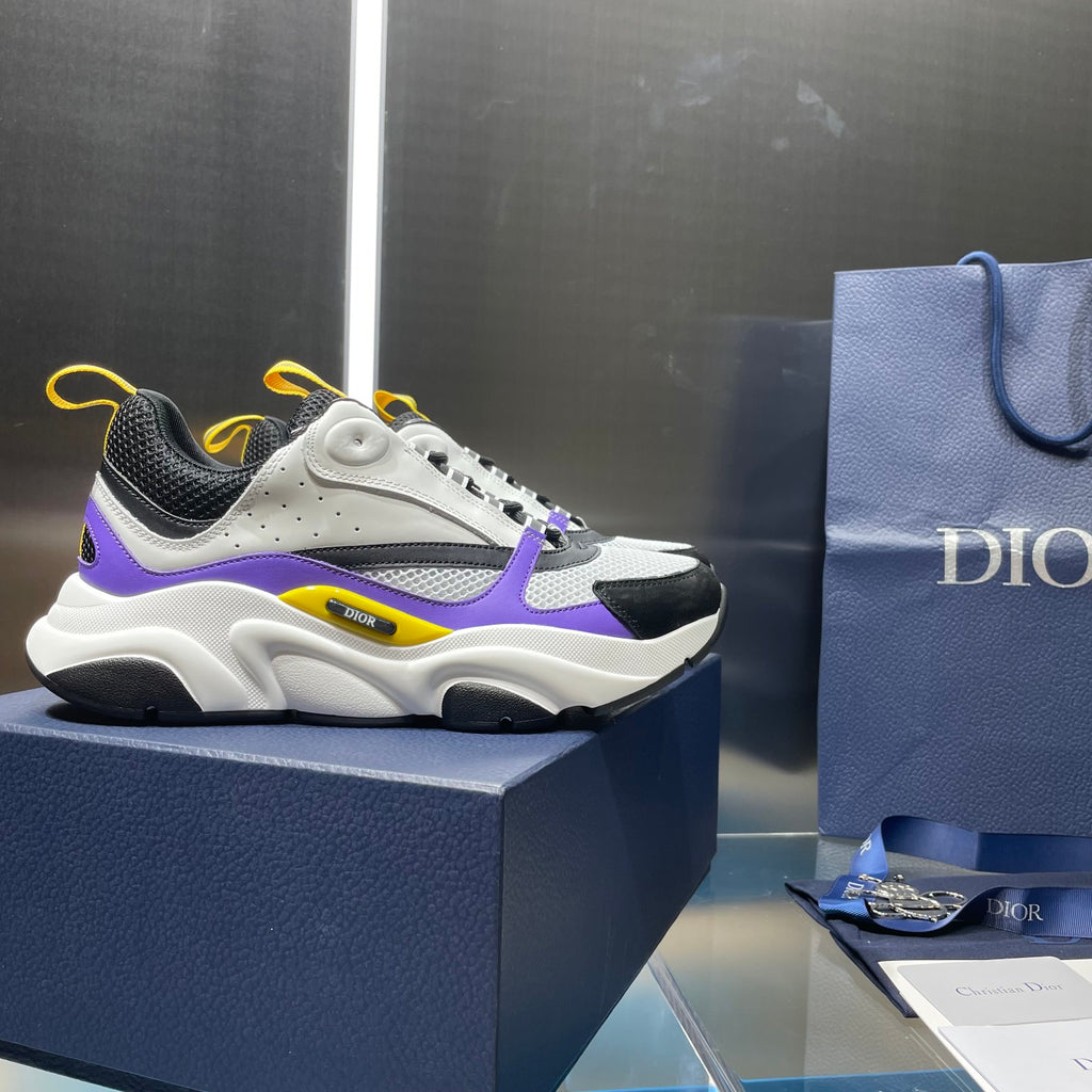 Dior chunky sneaker pair on box, white leather with black mesh, purple and yellow trims