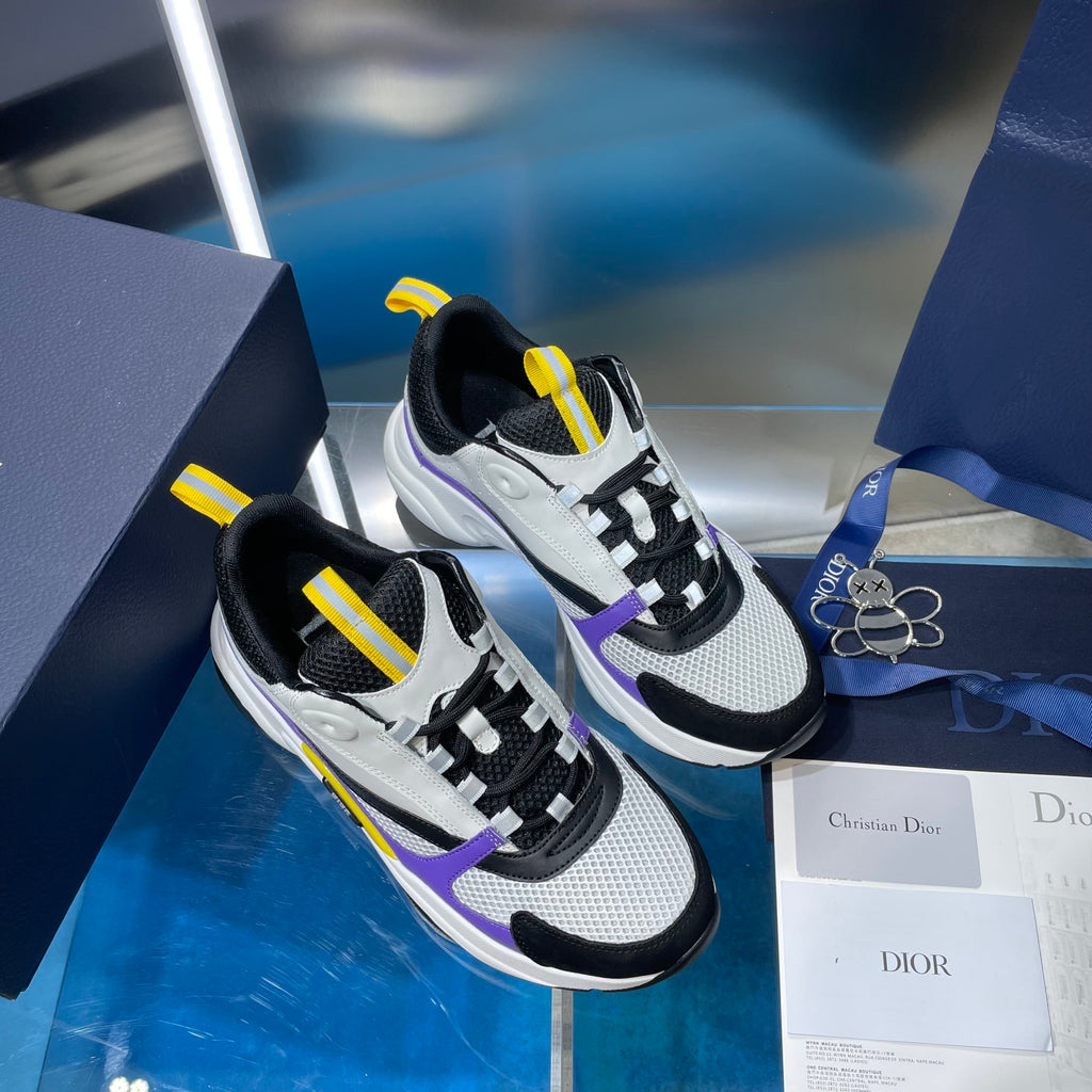 Dior unisex sneakers on box, black and white with purple strap detail and yellow tabs