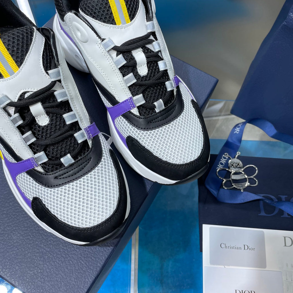 Dior sneakers close-up, white mesh and black panels with purple trim and yellow lace loops