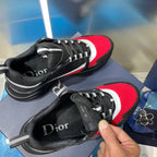 Unisex Dior lace-up sneakers, black mesh with red panels; hand holding one shoe