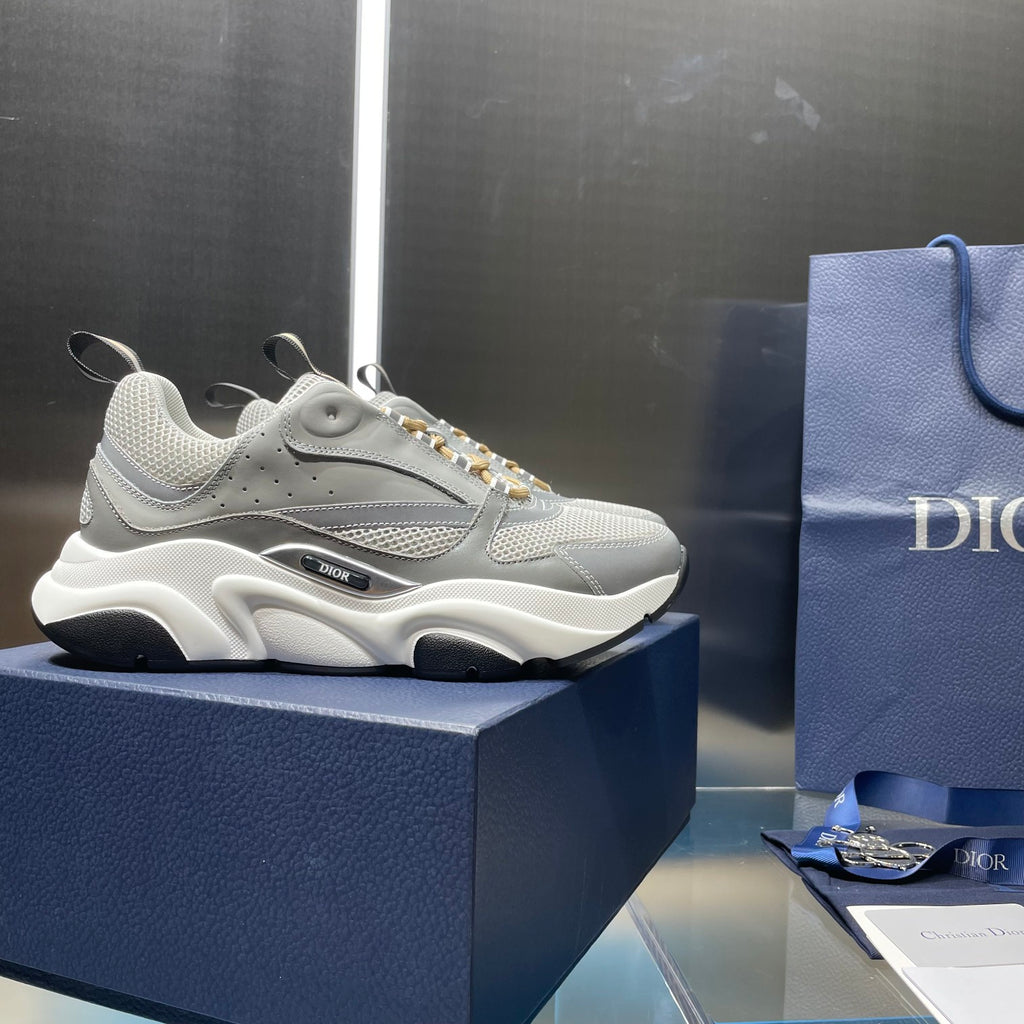 Unisex sneakers with light gray upper, gold laces, and chunky white midsole