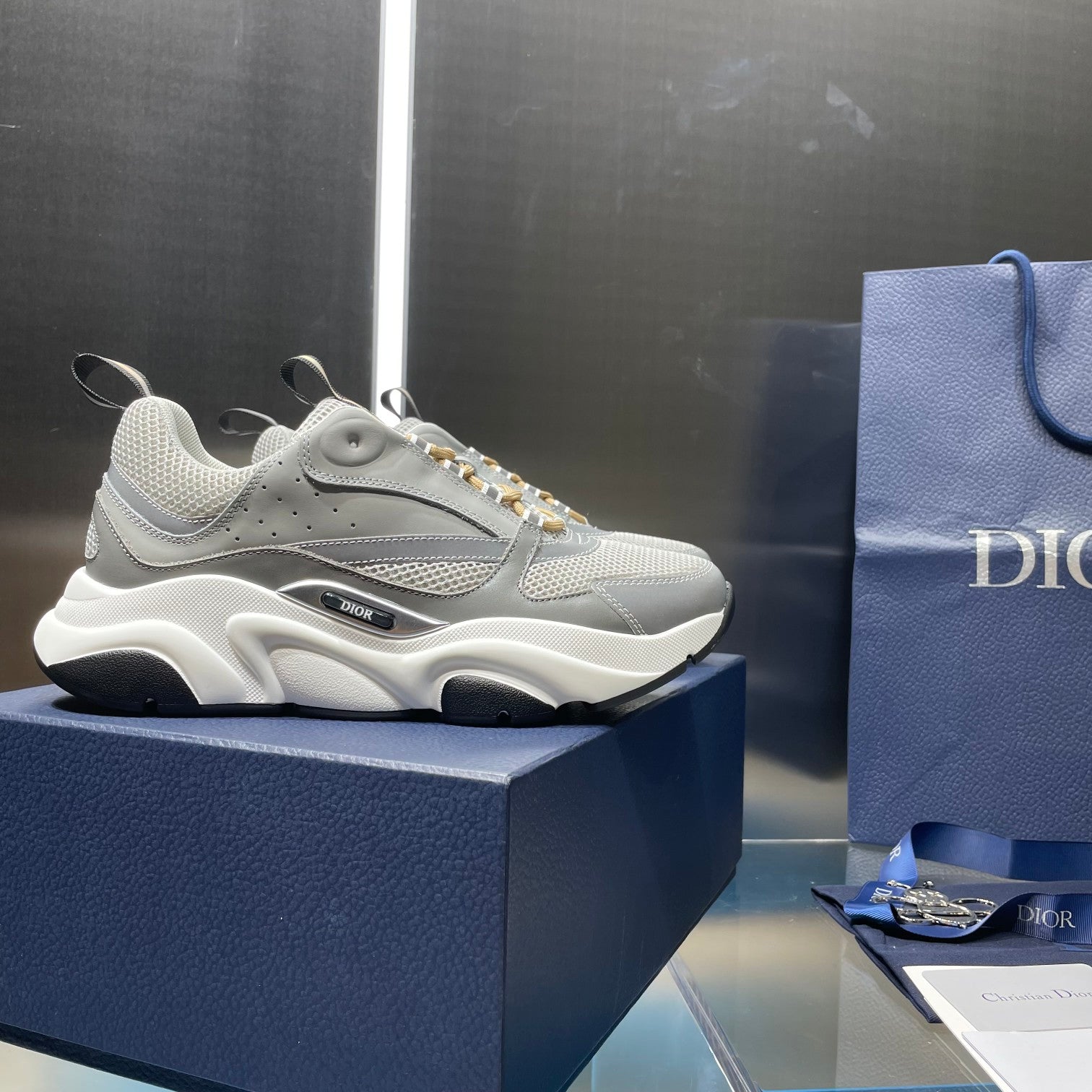 Unisex sneakers with light gray upper, gold laces, and chunky white midsole