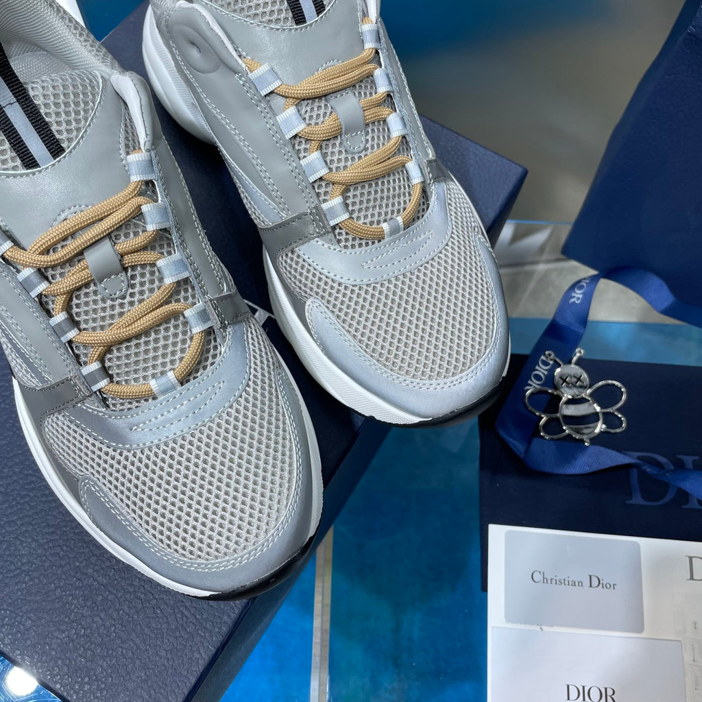 Close-up of unisex sneakers with light gray mesh upper and gold lace eyelets