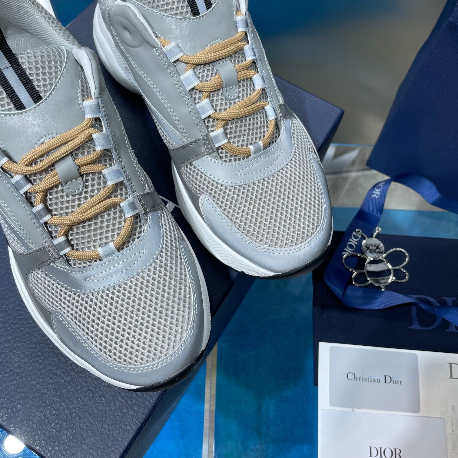 Close-up of unisex sneakers with light gray mesh upper and gold lace eyelets