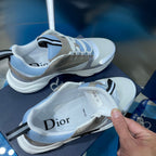 Unisex sneakers with light blue uppers and beige overlays, one shoe lifted