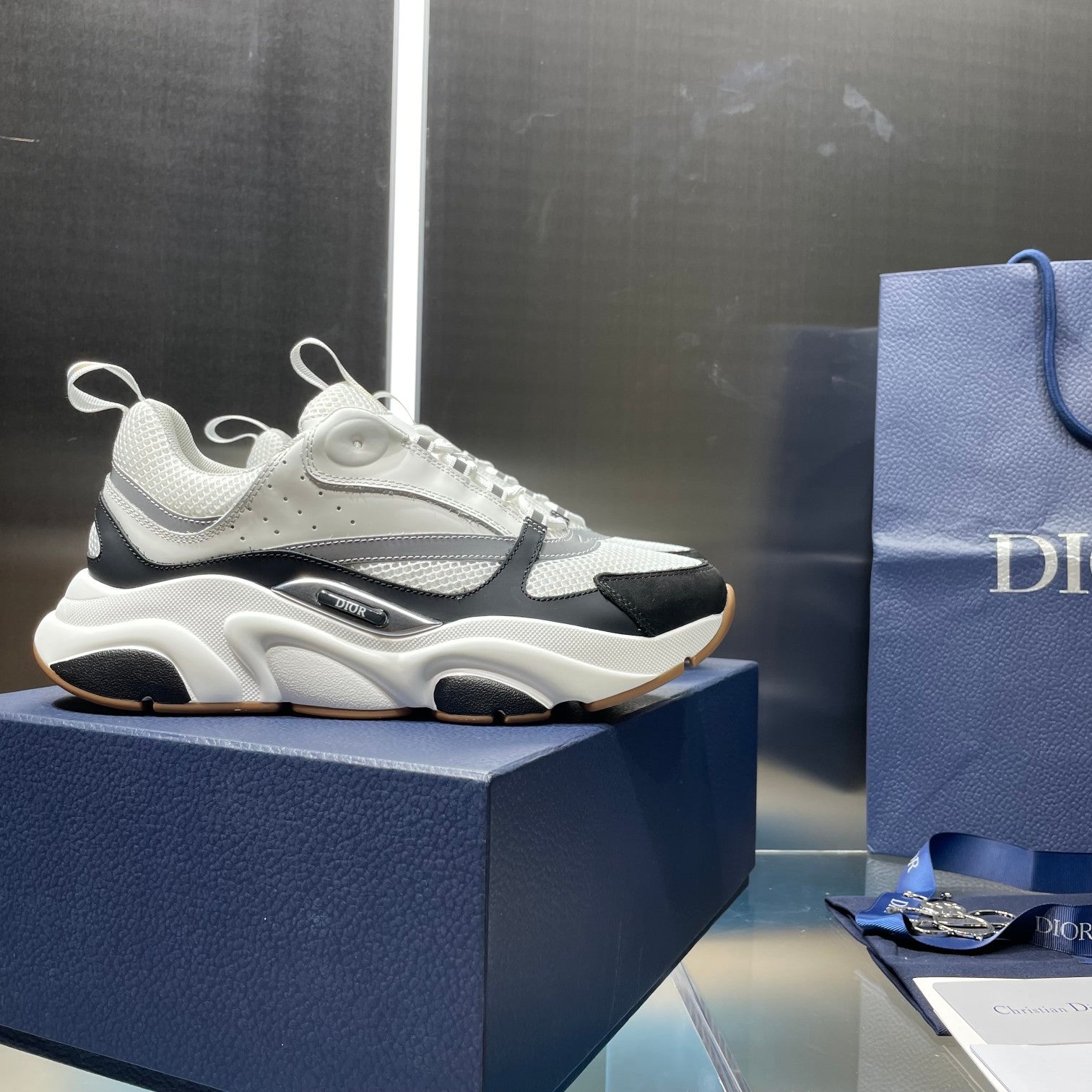 Unisex Dior sneakers on box, white mesh knit with black panel and tan outsole