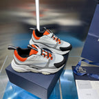 Dior unisex sneakers pair, white upper with orange collar and black overlays, lace-up.