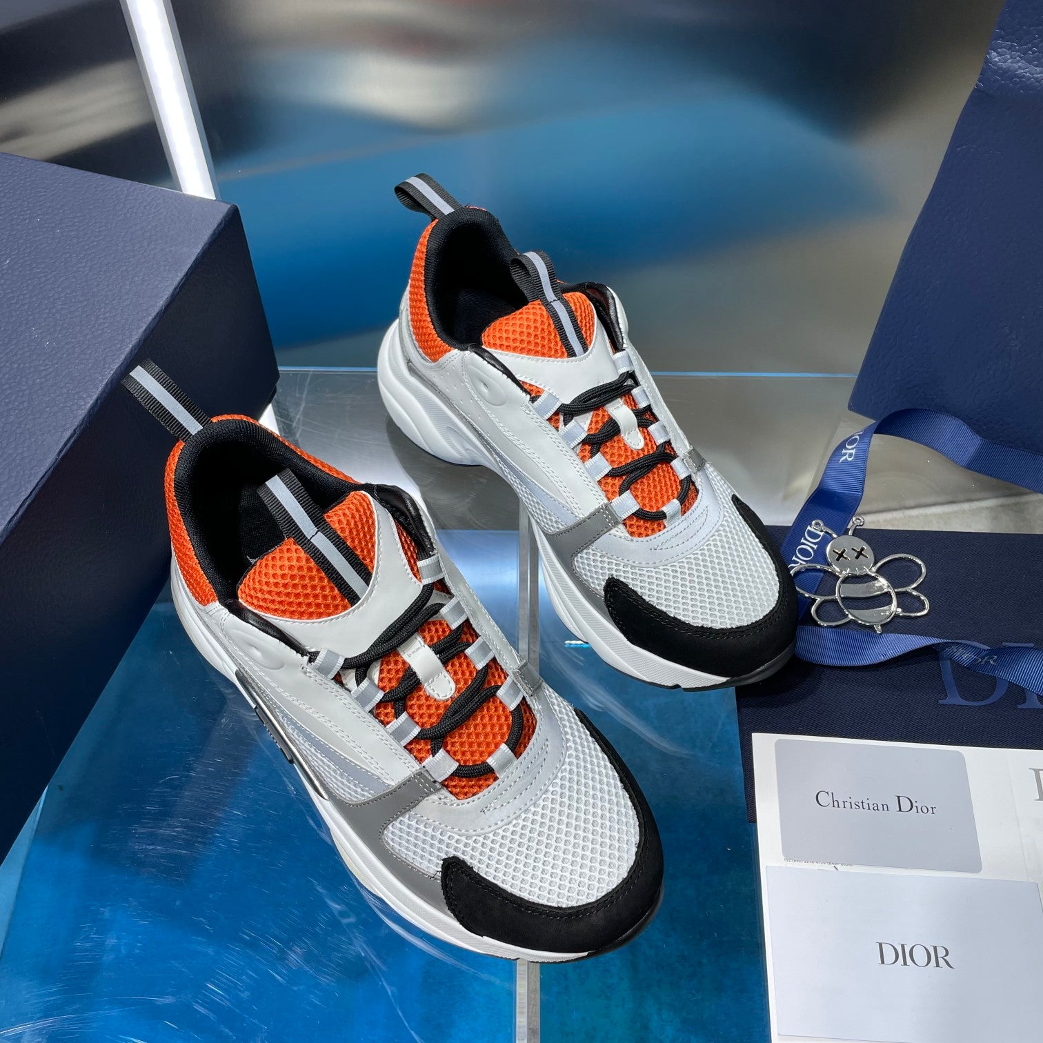 Dior unisex lace-up sneakers, white and gray knit with orange laces and black toe caps.
