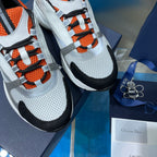 Dior unisex sneakers detail, orange lace pattern with white mesh panels and black trim.