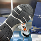 Dior unisex sneakers outsole view, textured gray rubber tread with CD logo badge.