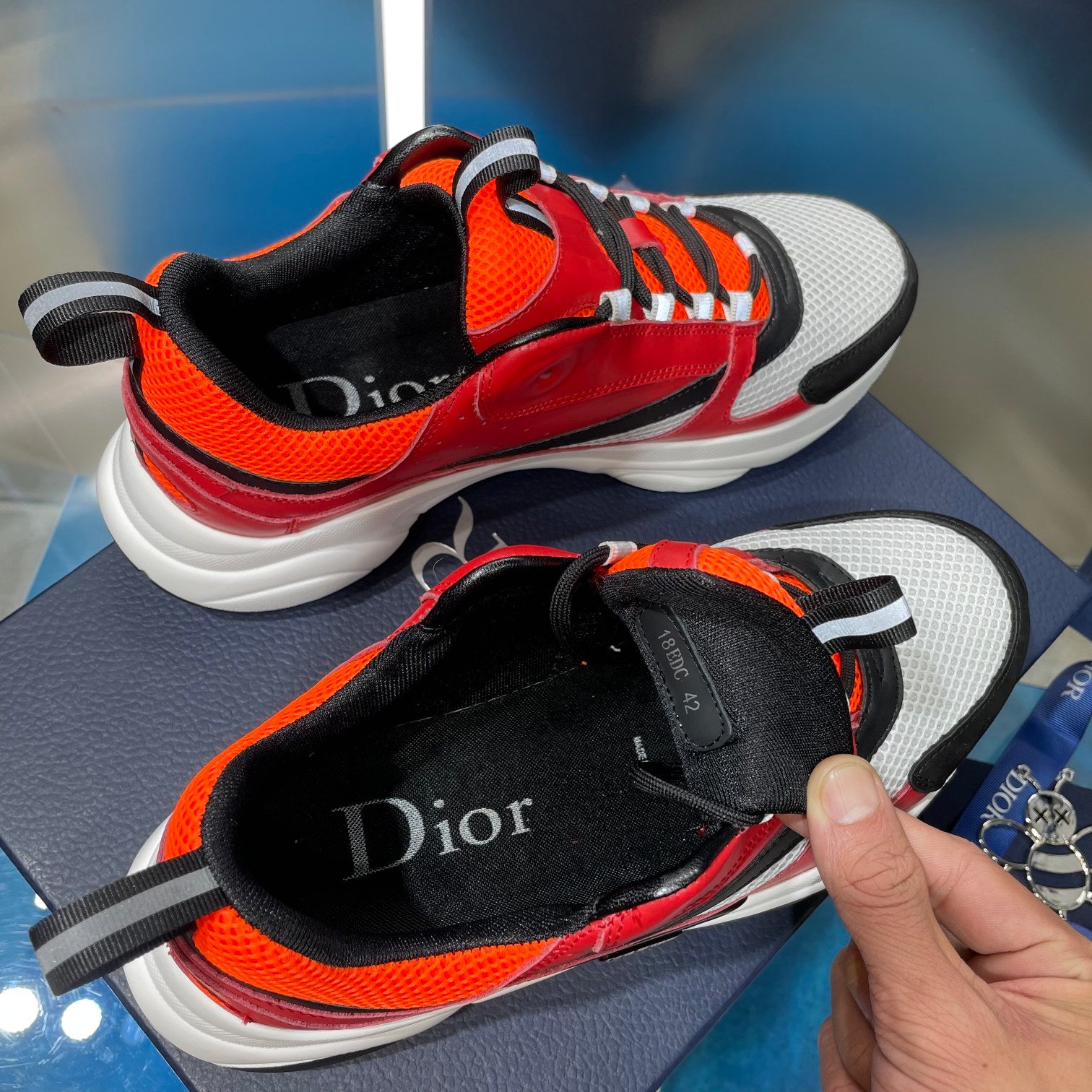 Dior sneaker interior with black lining, red and orange upper, and white sole edge