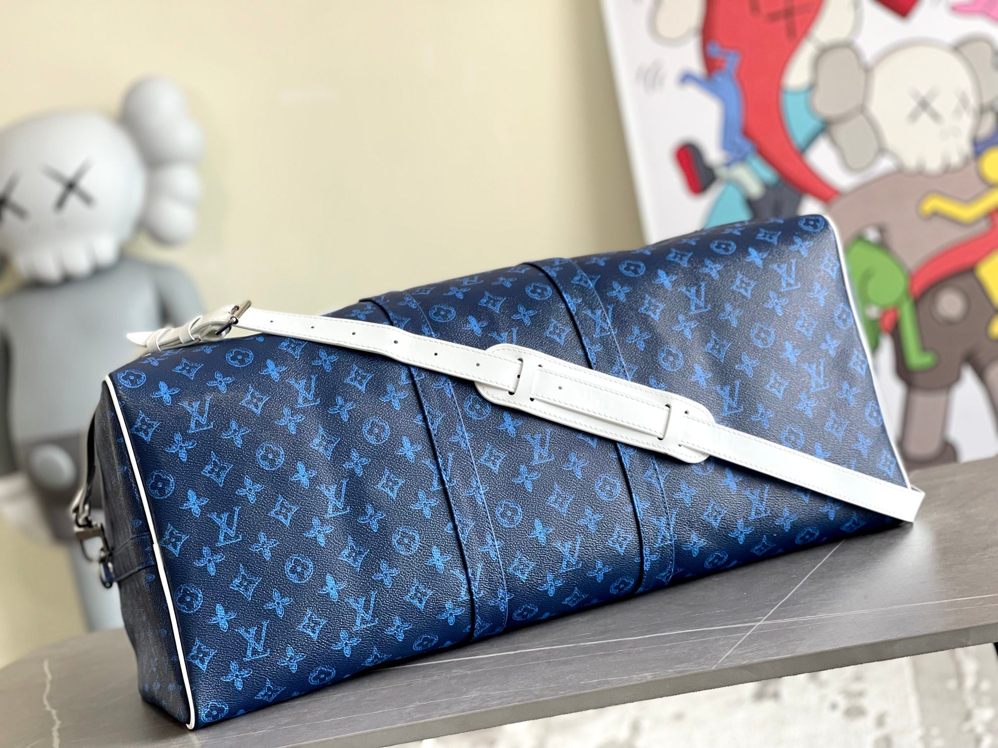 Blue monogram duffel bag with white-accent strap across the front
