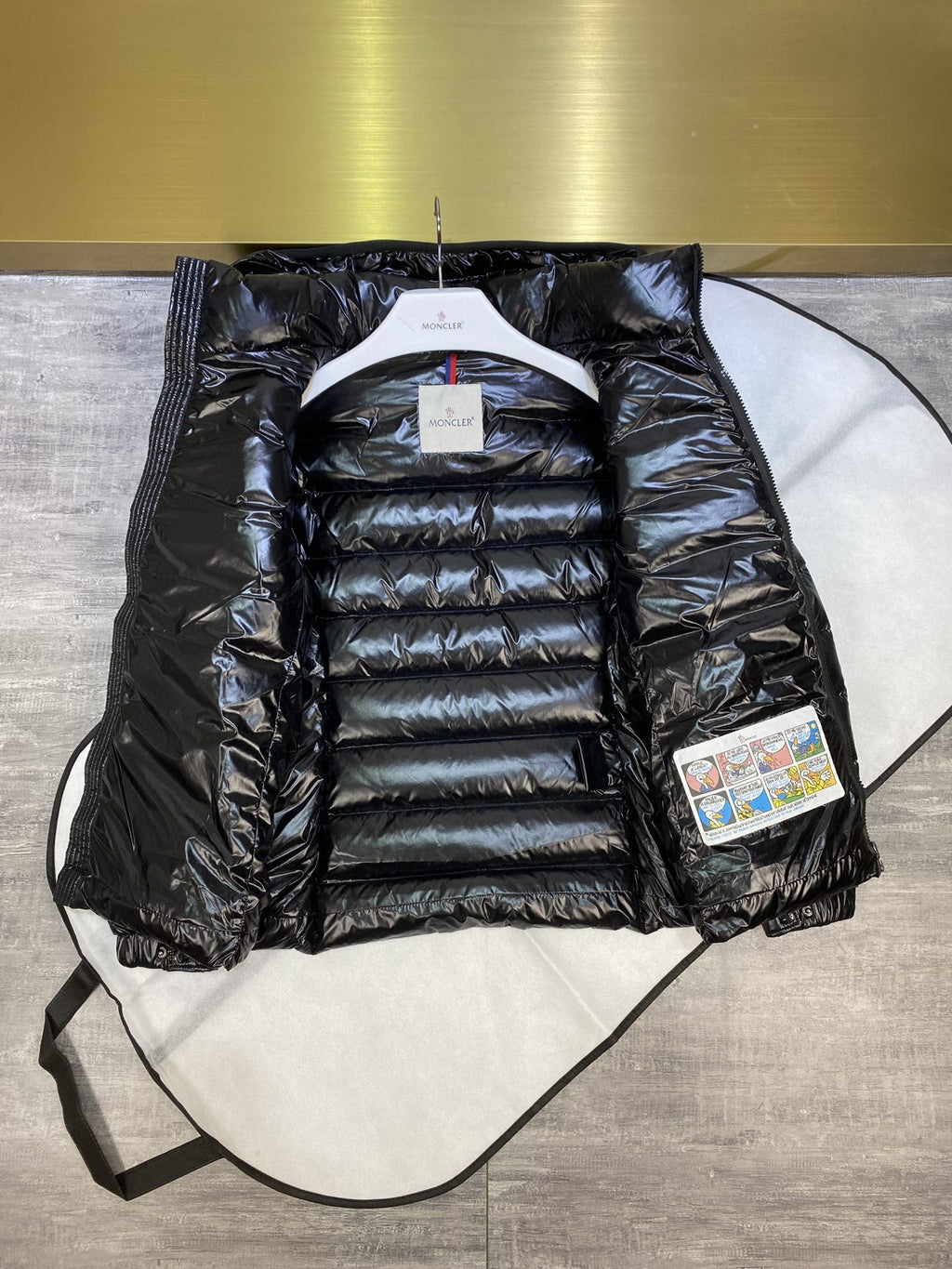 Dark puffer jacket with hood, full-zip front, quilted panels and attached tags