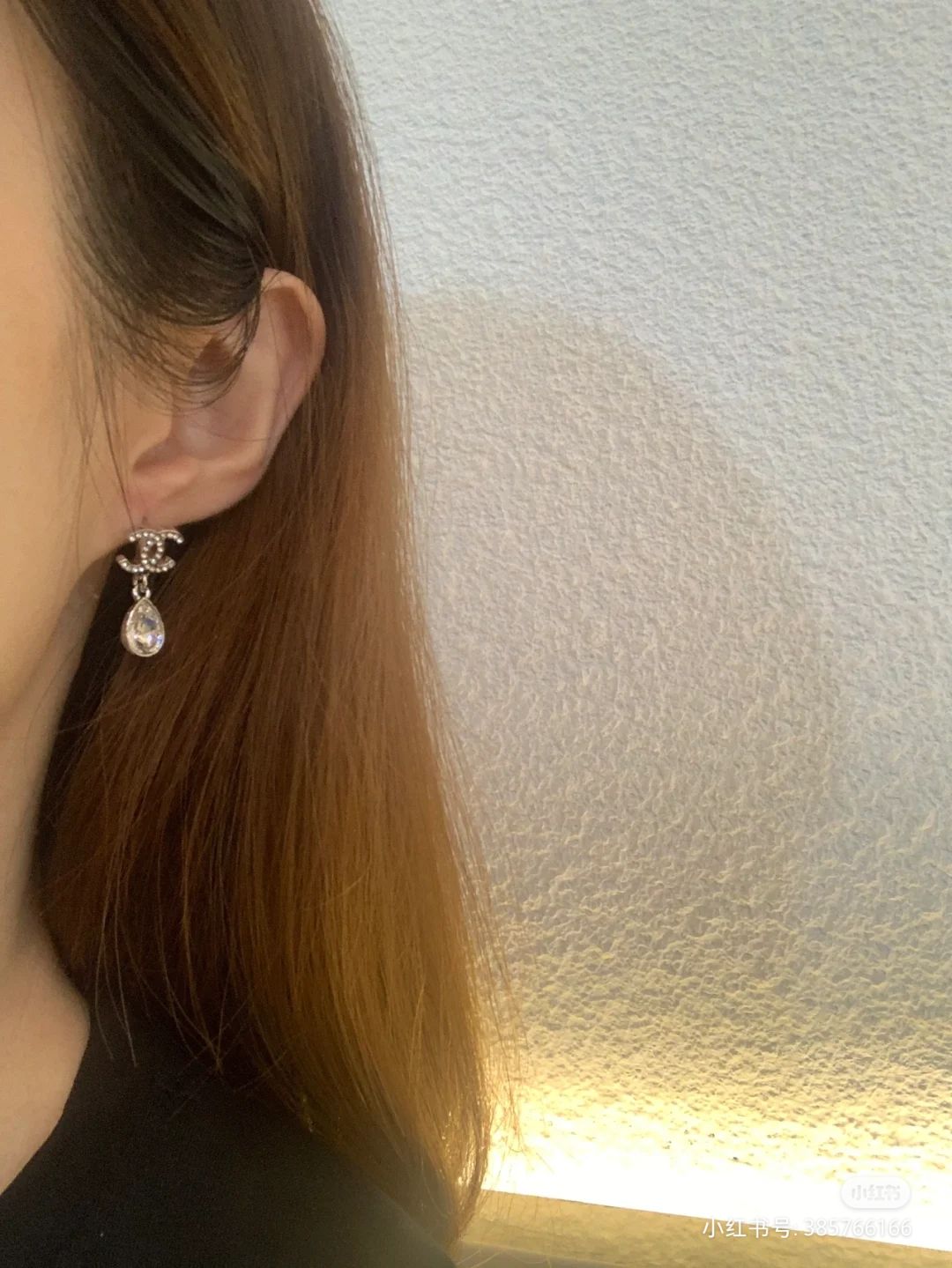 Silver-tone dangle earrings with teardrop crystal stones on ear